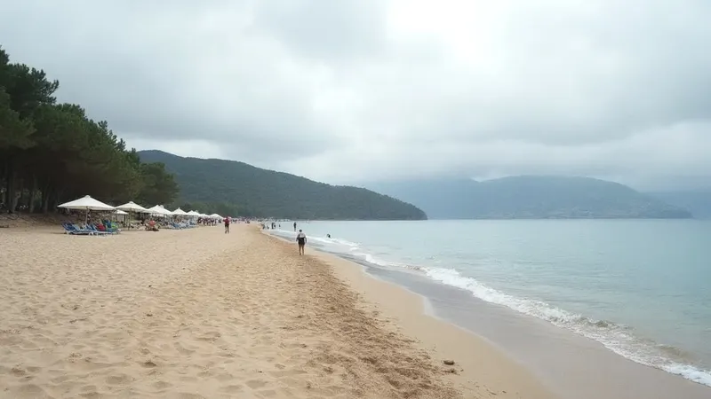 Sandstrand an der türkischen Riviera mit Liegen, Sonnenschirmen und bewaldeten Hügeln