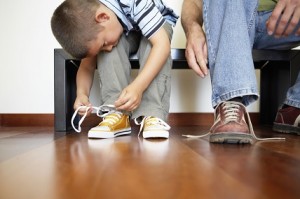 Kleiner Junge bindet sich die Schuhe